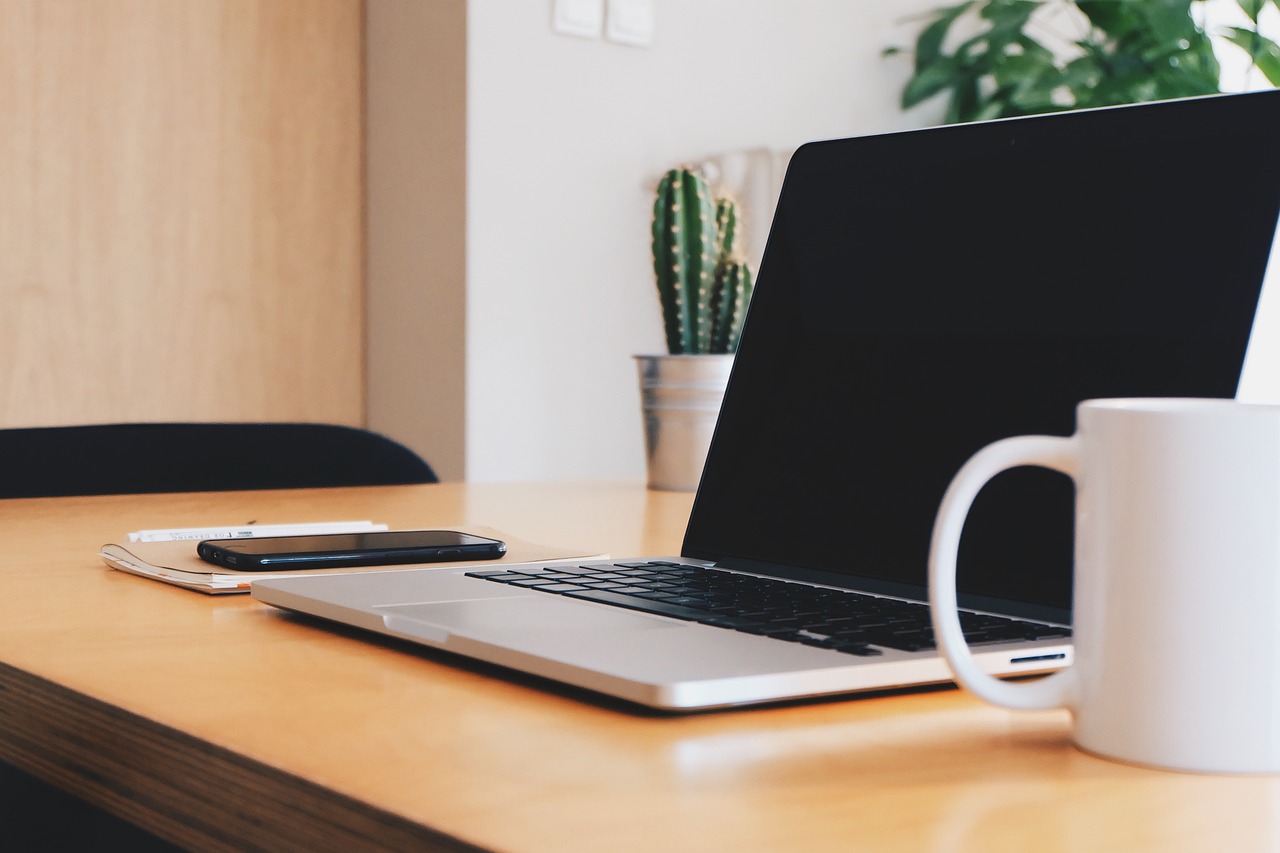 An open laptop and coffee mug on a clean, minimalist desk.
