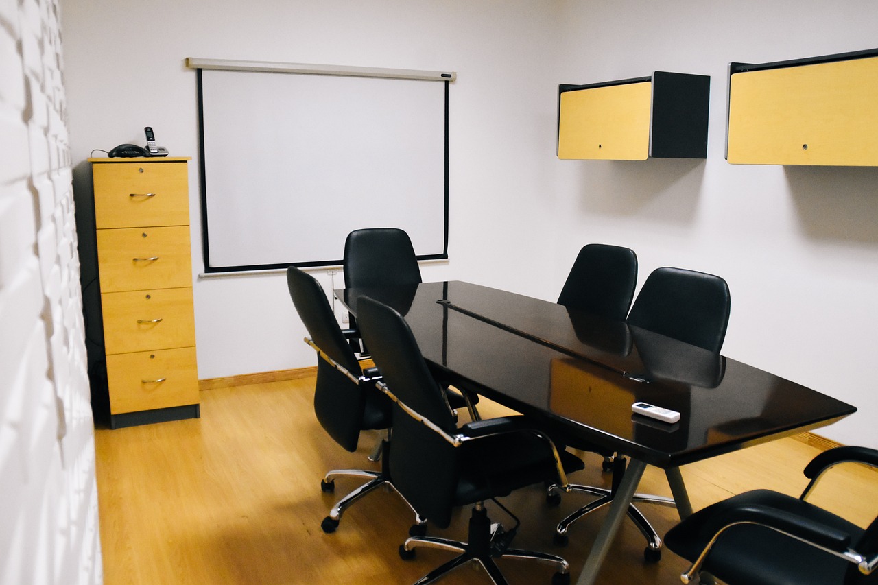 A conference table, chairs, and A minimalist, modern office conference room setup with table, chairs, projector screen, and cabinets.